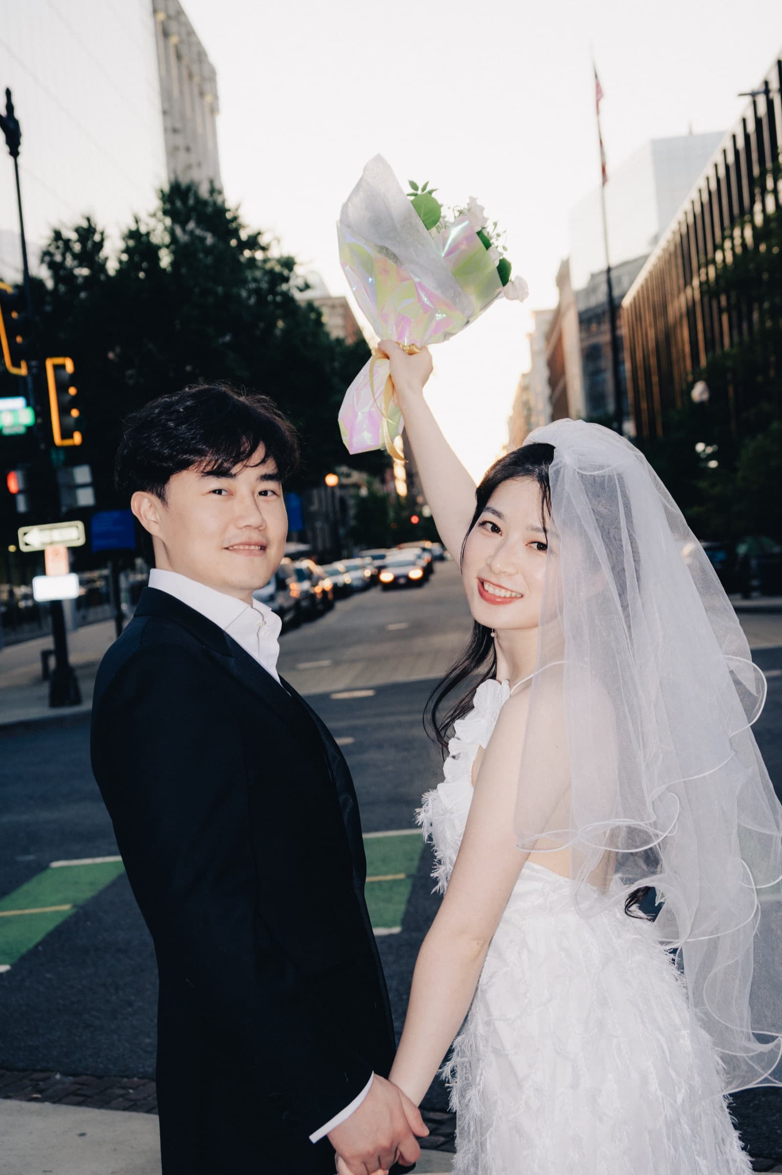 Couple celebrating on a city street with bouquet raised